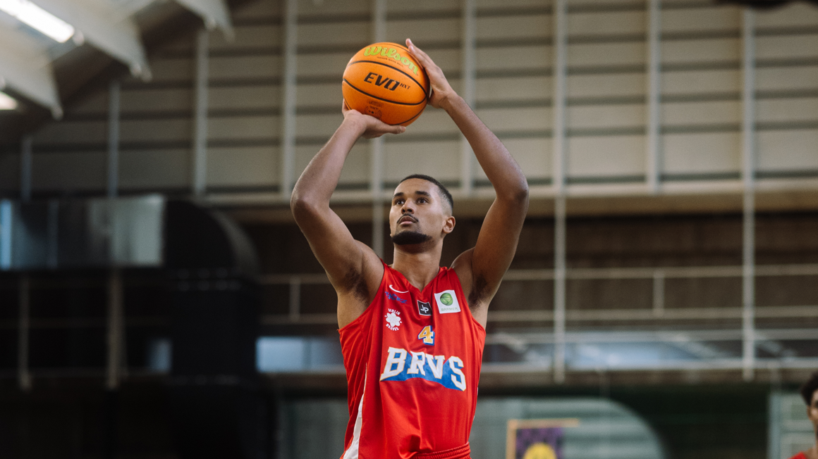 Foto: Ein Spieler der Berlin Braves hält zwischen seinen erhobenen Armen einen Basketball. 